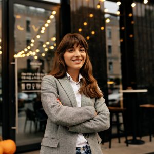 senora-traje-gris-sonriendo-camara-fondo-elegante-cafe-luces